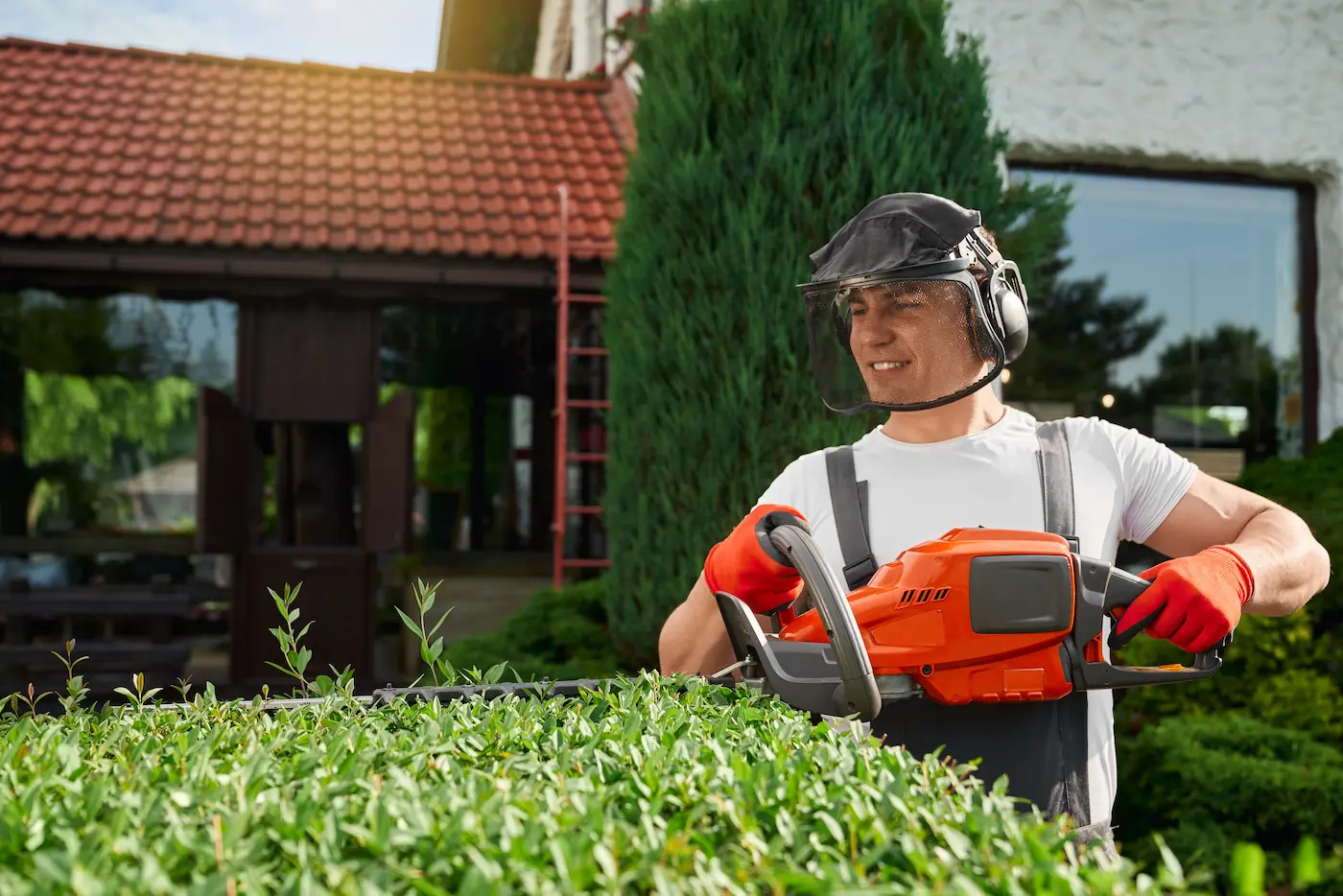 young-man-safety-mask-gloves-shaping-bushes